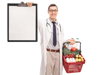 Young doctor holding a shopping basket full of groceries and a clipboard isolated on white background